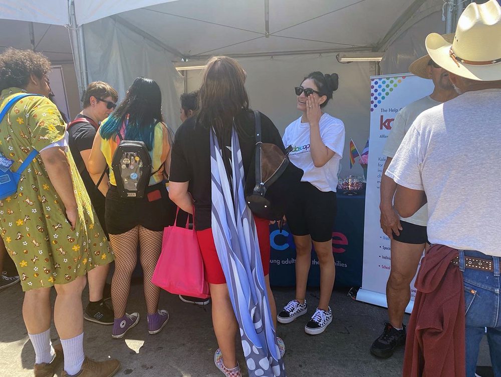 Staff members talking to a group of young adults at a pride event