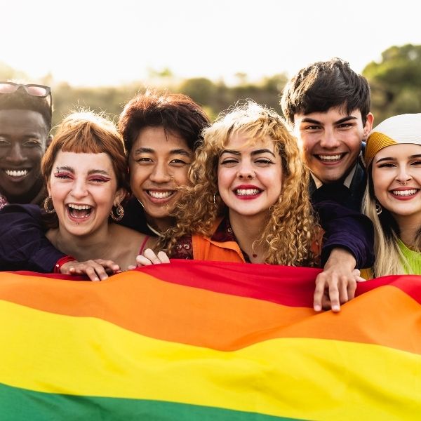 group of diverse teenagers holing up a rainbow flag